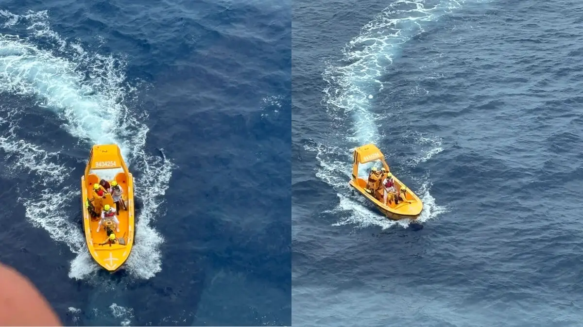 Two small yellow rescue boats with people wearing life jackets are moving through the blue ocean, leaving white wakes behind them. The boats are photographed from above.