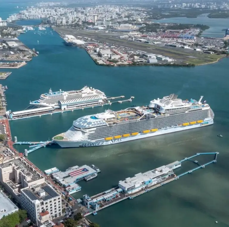 Aerial view of the cruise ship "Wonder of the Seas" docked at Pier 3 West in San Juan, with another cruise nearby. The image captures surrounding water, port facilities, and a cityscape in the background.