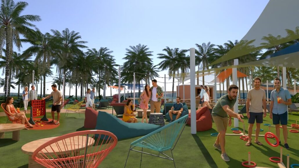 A group of people socialize and play lawn games on a grassy outdoor area at Great Stirrup Cay, Norwegian Cruise Line’s private island. Colorful seating and shade sails are scattered across the space under a clear sky.
