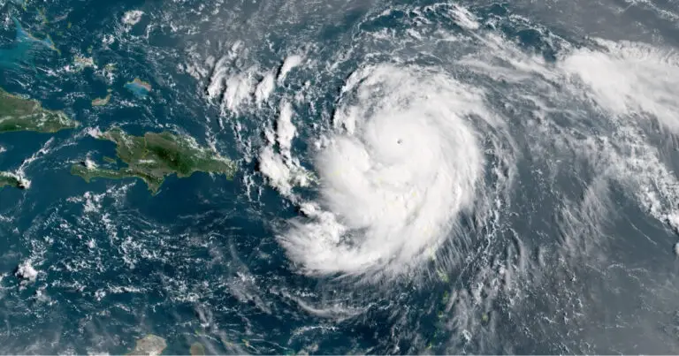 Satellite image of a Category 5 Hurricane with a visible eye over the Atlantic Ocean near the Caribbean islands, showing swirling clouds and bands extending outward from the storm center.