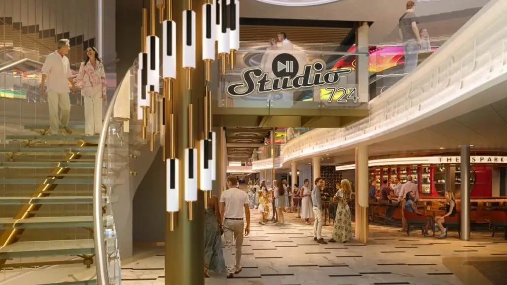 People walk through a modern, well-lit interior space with a large staircase and hanging light fixtures. A "Studio 724" sign is visible, along with shops and seating areas—reminiscent of Royal Caribbean’s signature onboard promenades.