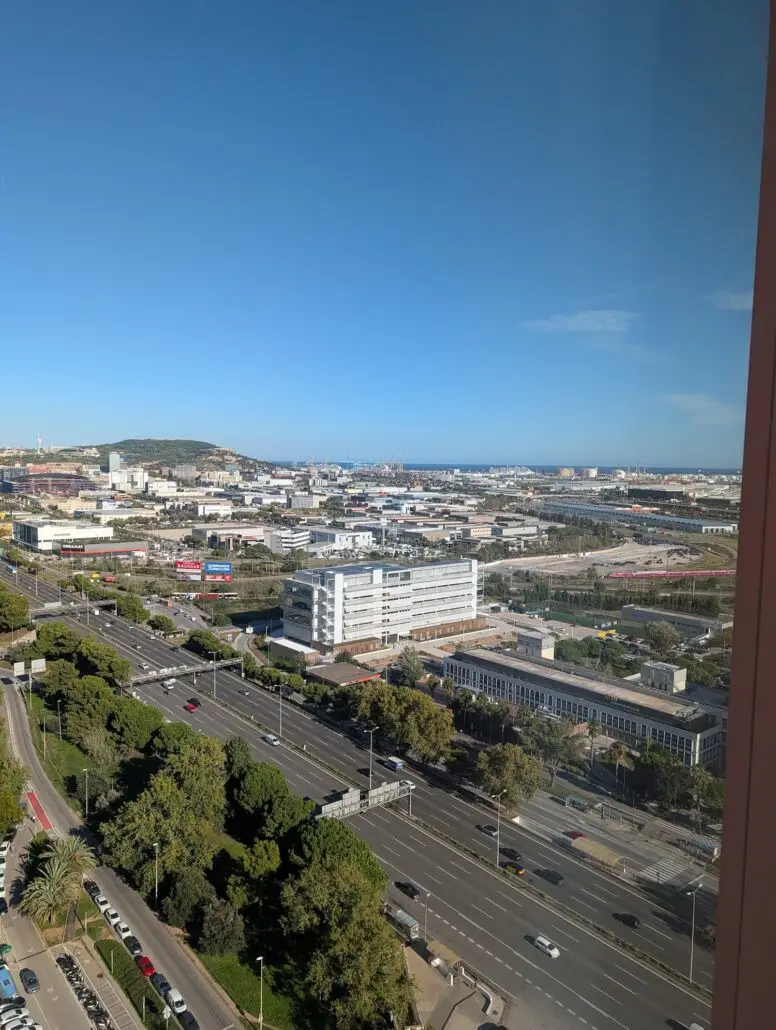 A wide cityscape view with highways, buildings, green spaces, and an industrial port in the background under a clear blue sky. The photo is taken from a high vantage point as the Star Princess prepares for its Inaugural Cruise.
