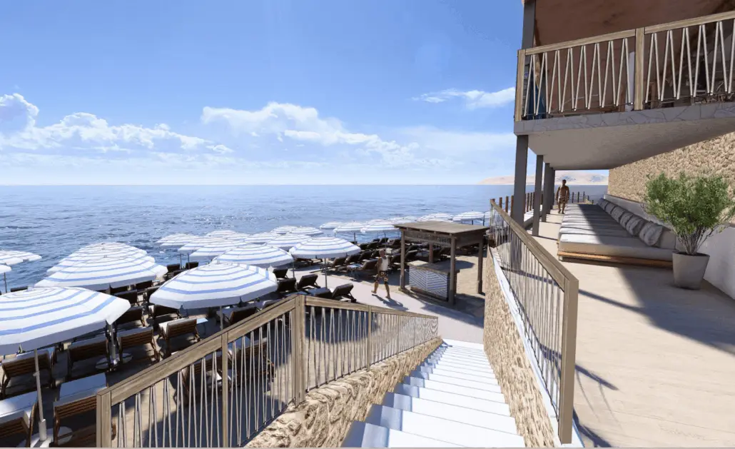 A seaside deck at Royal Beach Club Santorini, with lounge chairs and blue-and-white striped umbrellas for cruise guests. A balcony with cushioned seating overlooks the scene, set against a clear blue sky and calm ocean—perfect for Summer 2026 relaxation.