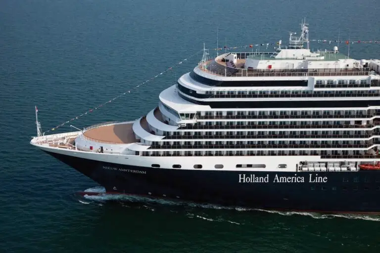 A large cruise ship labeled "Holland America Line" sails on calm blue water. The ship, offering Mexico Cruises and cultural workshops, has multiple decks with rows of balconies and people visible at the front. "Nieuw Amsterdam" is displayed on the bow.
