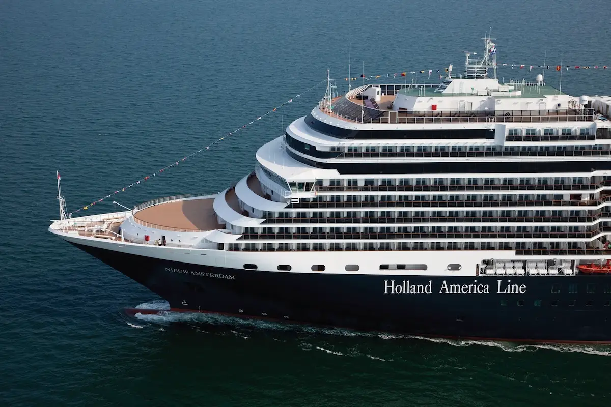 A large cruise ship labeled "Holland America Line" sails on calm blue water. The ship, offering Mexico Cruises and cultural workshops, has multiple decks with rows of balconies and people visible at the front. "Nieuw Amsterdam" is displayed on the bow.