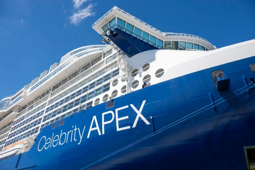 Close-up view of the Celebrity Apex cruise ship’s blue and white exterior, several rows of windows, and the bridge against a clear blue sky—perfect for Seven-Night Cruises from Florida's Space Coast.