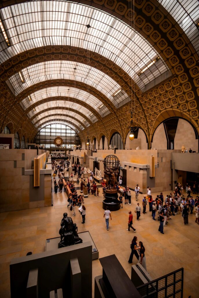 Interior view of a large museum hall with a high arched glass ceiling, patterned walls, sculptures, and groups of visitors—an inspiring highlight for first-time visitors to Spain seeking top Spain tourism experiences.