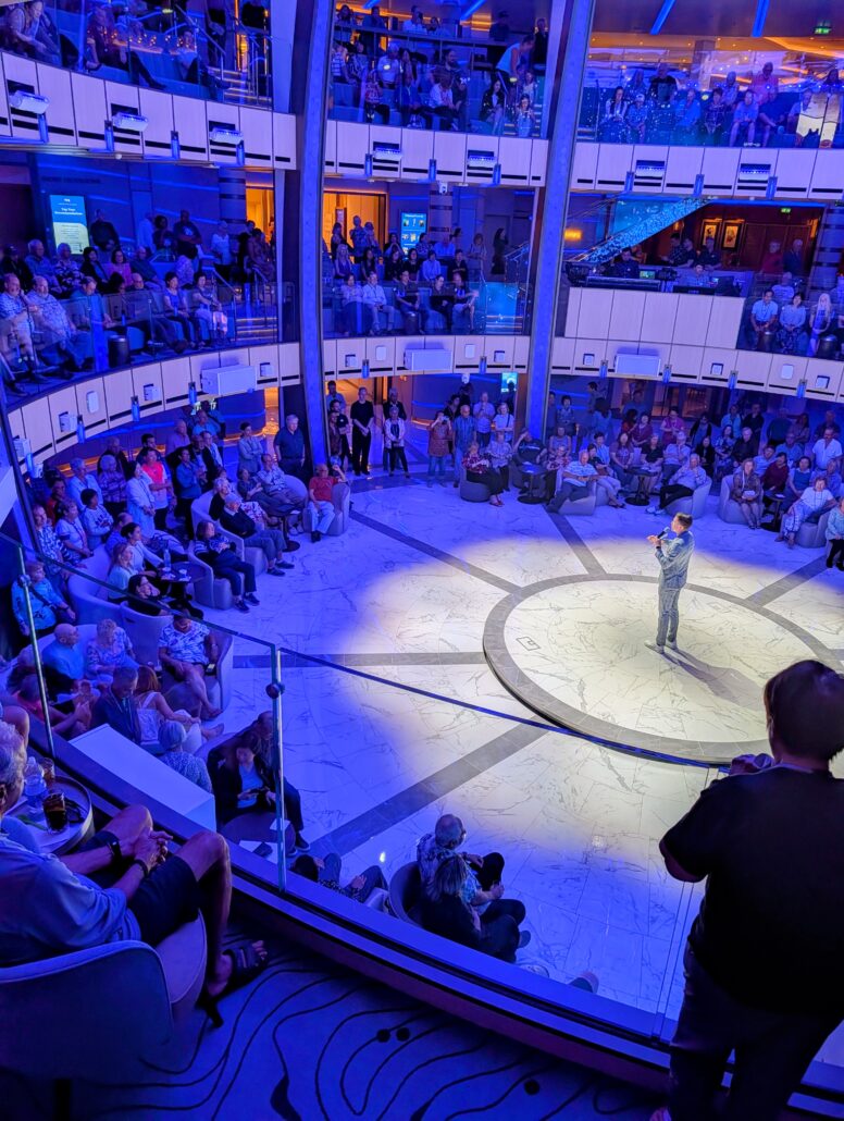 A man on a stage entertains a crowd as part of the nightly entertainment aboard the Star Princess at Princess Cay.