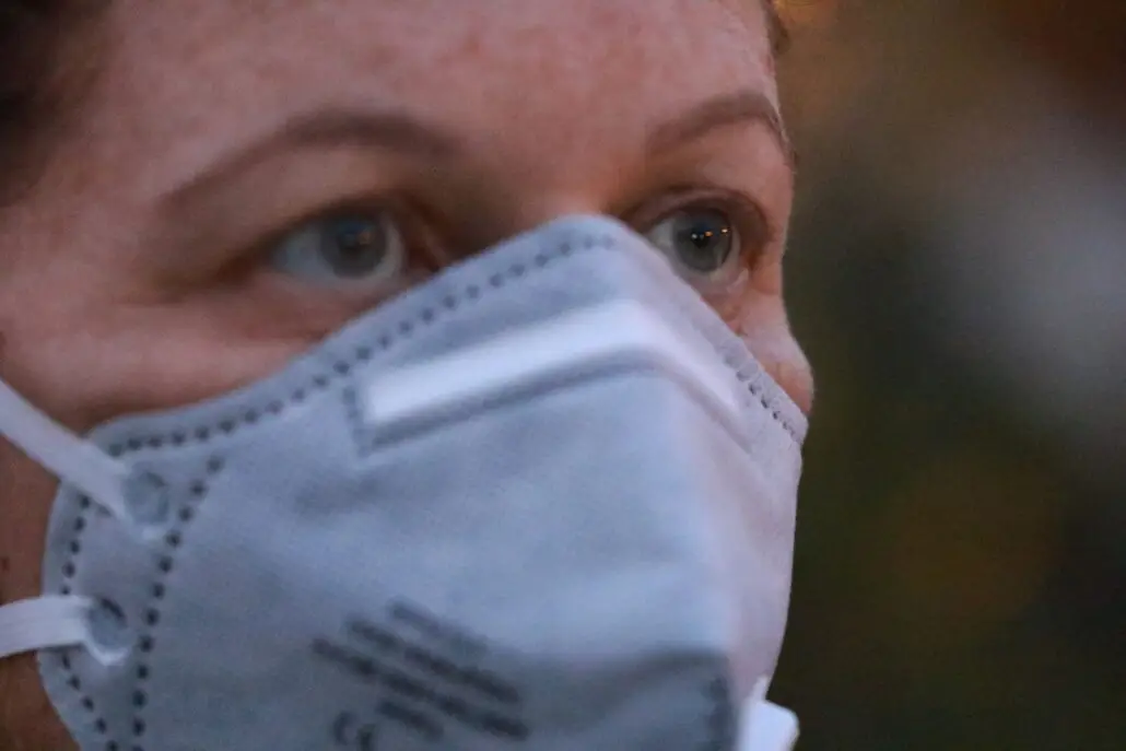 Close-up of a person wearing a grey protective face mask, with only their eyes visible, looking ahead—a precautionary measure during the recent Norovirus outbreak. The background is out of focus.