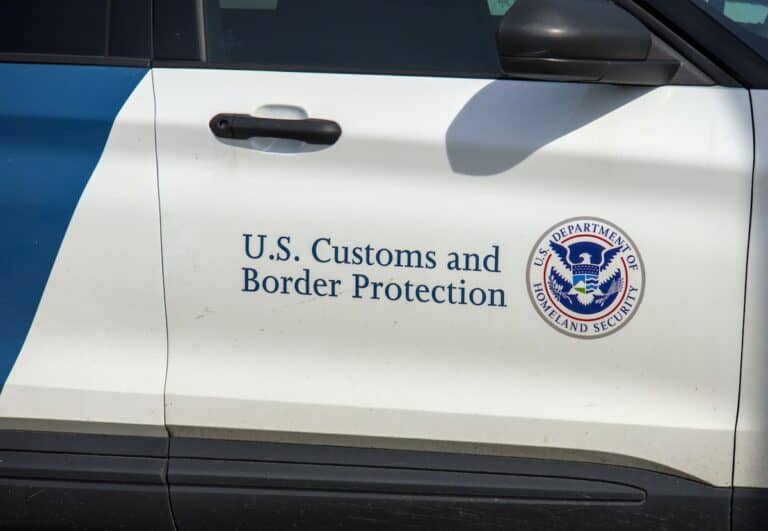 Close-up of a vehicle door with the U.S. Customs and Border Protection logo and text, highlighting a federal operation near San Diego, along with the U.S. Department of Homeland Security emblem.