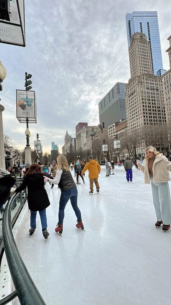 People ice skating on an outdoor rink surrounded by Chicago architecture.